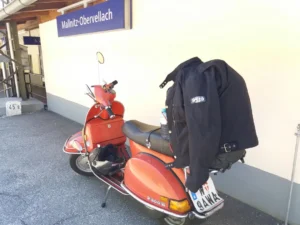 Rote Vespa auf Rollertour durch Österreich am Bahnhof Mallnitz