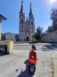 Rote Vespa auf Rollertour durch Österreich vor dem Stift Admont
