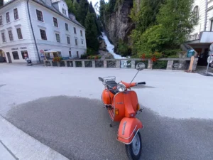 Rote Vespa auf Rollertour durch Österreich vor dem Wasserfall in Bad Gastein